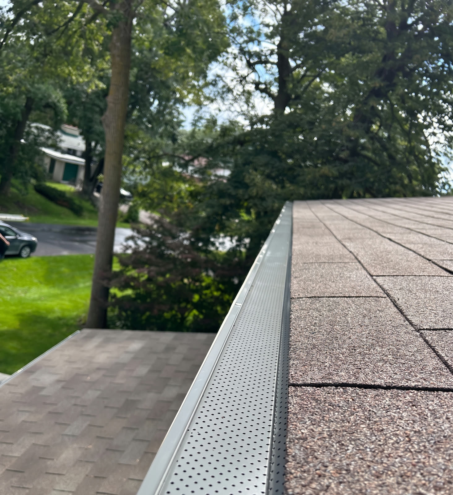 A newly installed perforated aluminum gutter guard along the eaves